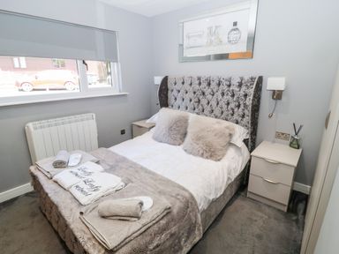 A bedroom with a double bed two bedside tables and a window at Lodge 32 Otterburn