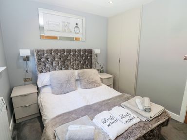 A bedroom with a bed with two pillows bedside tables and a wardrobe at Lodge 32 in Otterburn