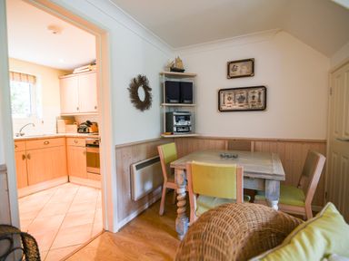 A dining area with a wooden table and chairs next to a kitchen with wooden cabinets at 52 Fernhill Heights in Charmouth