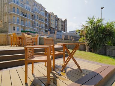 A garden area with wooden furniture and buildings in the background at 11 Cove View Apartments Ilfracombe