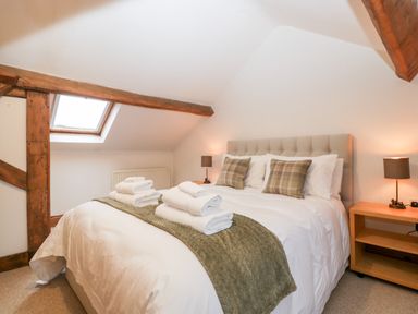 A bedroom with a double bed two bedside tables with lamps and a skylight window at Bullfinch Cottage in Kingsland