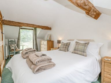 A bedroom with a bed with folded towels and pillows a wooden chair and chest of drawers at Fieldfare in Kingsland