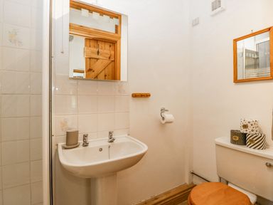 A bathroom with a sink a mirror a toilet with rolls of toilet paper and a wooden toilet seat at Fieldfare in Kingsland