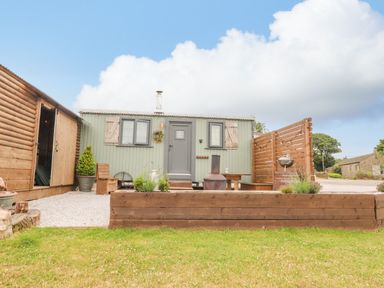An outdoor area with a small green cabin wooden fencing and garden furniture at Heather Hut at Copy House Hideaway in Earby