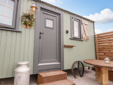 Exterior of a green wooden hut with a grey door and window at Heather Hut at Copy House Hideaway in Earby