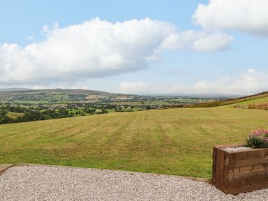 A grassy field with hills and a partly cloudy sky at Heather Hut at Copy House Hideaway in Earby