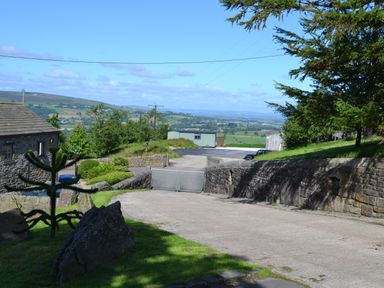 A driveway with stone walls and gate overlooking countryside at Heather Hut at Copy House Hideaway in Earby