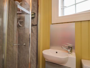 A bathroom with a shower enclosure and a sink next to a window at Heather Hut at Copy House Hideaway in Earby