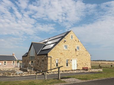 A stone building with solar panels on the roof and a smaller brick building nearby at Whinny Cottage in Embleton