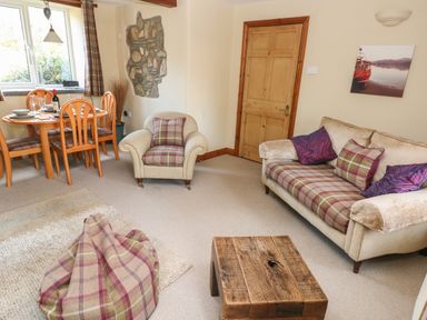 A living room with a sofa armchair dining table wooden door and a wooden coffee table at 2 Yr Hen Felin in Castle Morris near Letterston