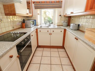 A kitchen with cabinets a sink microwave stove and countertop appliances at 2 Yr Hen Felin Castle Morris near Letterston