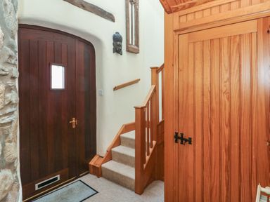 An entrance hall with a wooden door stone wall stairs and wooden panel walls at 2 Yr Hen Felin Castle Morris near Letterston