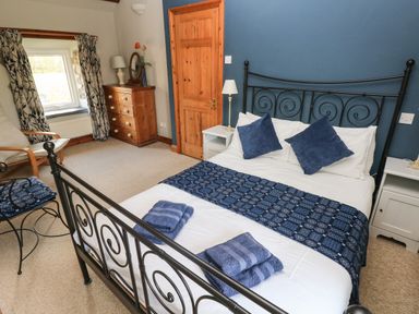 A bedroom with a black metal bed frame and blue and white bedding at 2 Yr Hen Felin in Castle Morris near Letterston