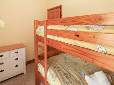 A bedroom with a wooden bunk bed and a white dresser at 2 Yr Hen Felin in Castle Morris near Letterston