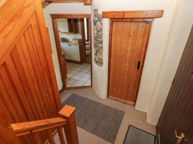 A hallway with wooden stairs wooden doors and a view into a kitchen at 2 Yr Hen Felin Castle Morris near Letterston