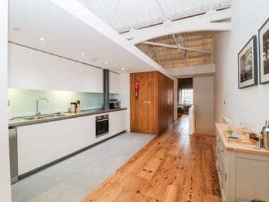 A kitchen with white cabinets and wooden floor at Clarence Riverside Royal William Yard in Plymouth