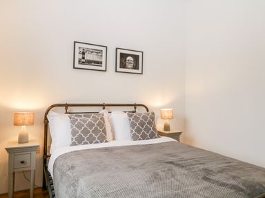 A bedroom with a double bed two bedside tables two lamps and two framed pictures on the wall at Clarence Riverside Royal William Yard in Plymouth