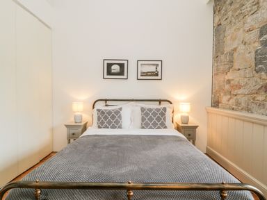A bedroom with a bed between two bedside tables with lamps and two framed pictures on the wall at Clarence Riverside Royal William Yard in Plymouth