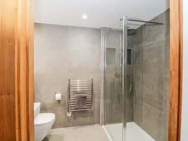 A bathroom with a wall-mounted toilet, shower enclosure, towel rack with towel at Clarence Riverside Royal William Yard in Plymouth