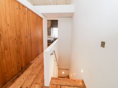 A staircase with wooden steps and railing next to a hallway with wooden floor and wall at Clarence Riverside Royal William Yard in Plymouth