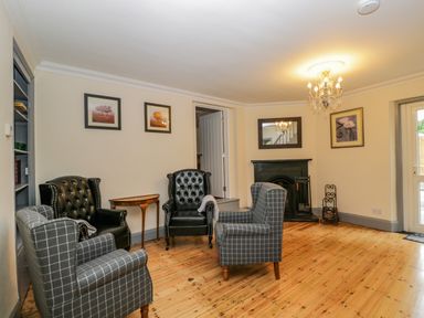 A sitting room with four armchairs a fireplace and framed pictures on the walls at White Roses in Whitchurch near Monmouth