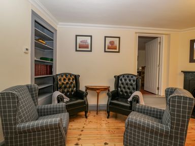 A seating area with two black leather armchairs two checked fabric armchairs and a wooden side table at White Roses Whitchurch near Monmouth