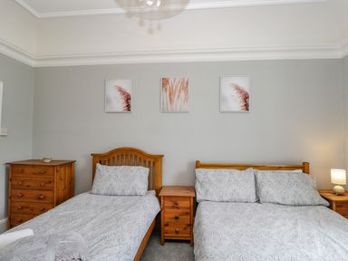 A bedroom with two wooden beds and matching furniture and three framed pictures on wall at White Roses in Whitchurch near Monmouth