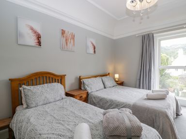 A bedroom with two beds bedside tables and a window with curtains at White Roses in Whitchurch near Monmouth