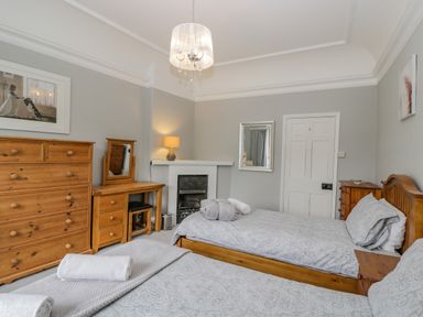 A bedroom with two single beds wooden furniture and a lit lamp at White Roses in Whitchurch near Monmouth