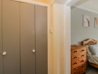 A wardrobe with grey doors and white knobs next to a wooden chest of drawers and a bed in a bedroom at White Roses Whitchurch near Monmouth