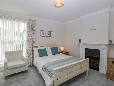 A bedroom with a bed armchair fireplace and window blinds at White Roses in Whitchurch near Monmouth