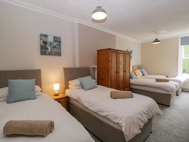 A bedroom with three single beds a wooden wardrobe and a nightstand with a lamp at White Roses in Whitchurch near Monmouth