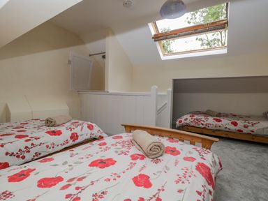 A bedroom with three single beds under a skylight window at White Roses in Whitchurch near Monmouth
