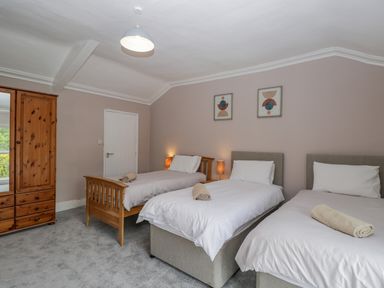 A bedroom with three single beds two bedside lamps wooden wardrobe and two framed pictures on the wall at White Roses in Whitchurch near Monmouth