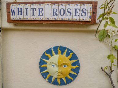 A wall with a sign spelling white roses above a sun and moon ceramic decoration at White Roses in Whitchurch near Monmouth