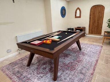 A game room with a pool table and dart board a wooden door on a rug at White Roses in Whitchurch near Monmouth