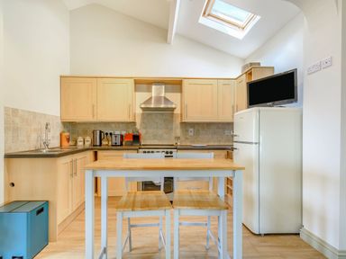 A kitchen with wooden cabinets a dining table with stools a refrigerator and a skylight at The Paddock in Honington near Shipston-On-Stour