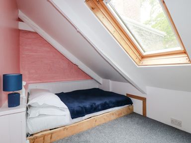 A small bedroom with a single bed under a slanted ceiling and a skylight window at The Cottage in St Kew