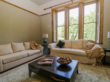 A living room with two sofas a coffee table and large windows at The Residence in Cleator