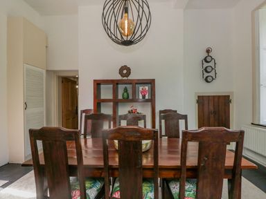 A dining room with six wooden chairs around a wooden table a wooden shelving unit and a wall clock at The Residence in Cleator