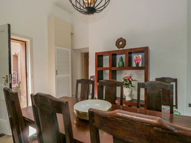 A dining room with a wooden table and chairs a bowl on the table and a wooden shelf with decorative items at The Residence in Cleator