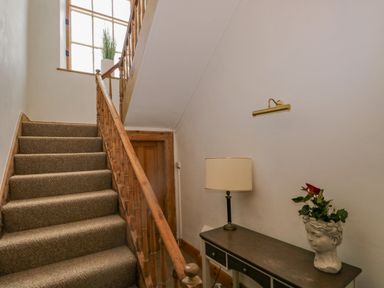 A staircase with carpeted steps a wooden handrail a small table with a lamp and a head-shaped plant pot at The Residence in Cleator