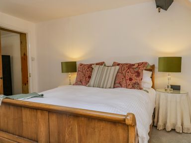 A bedroom with a wooden bed frame white bedding green and patterned pillows and two bedside tables with lamps at The Residence in Cleator