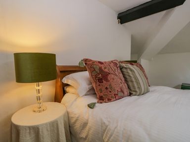 A bedroom with a bed with patterned pillows and a table with a lamp at The Residence in Cleator
