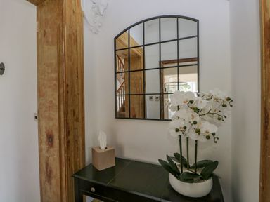 A console table with a tissue box and white orchid plant under a grid mirror at The Residence in Cleator