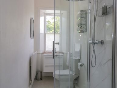 A bathroom with a shower, toilet, sink, and window at The Residence in Cleator