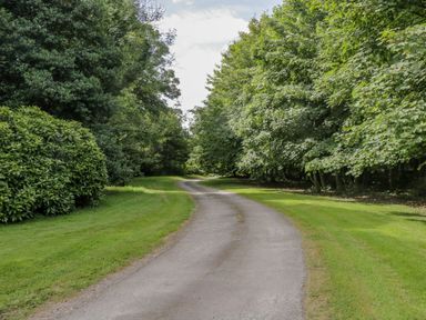 A winding paved path surrounded by grass and trees at The Residence in Cleator