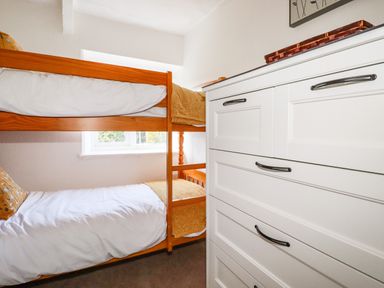 A bedroom with wooden bunk beds and a white dresser at Gwynn Cottage in St Mabyn