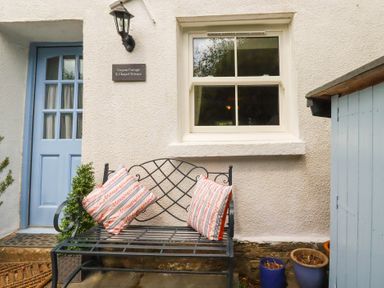 An outdoor seating area with a bench and cushions at Gwynn Cottage St Mabyn