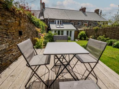A garden with a table and chairs at Gwynn Cottage, St Mabyn